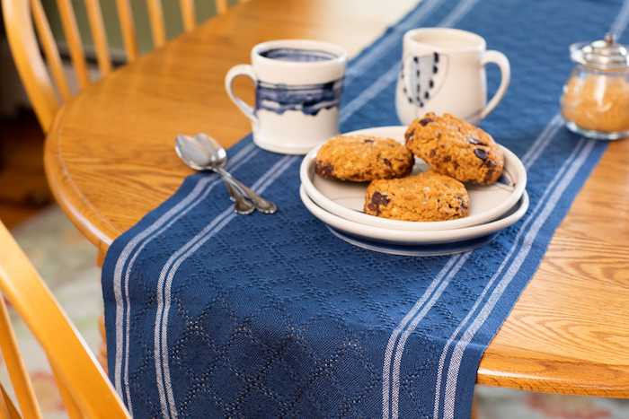 table set with huck lace runner, tea mugs and cookies
