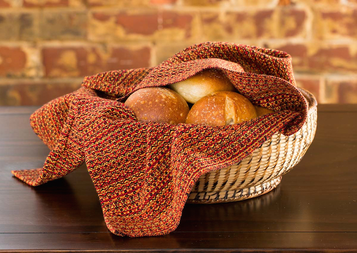 Letting Go kitchen towel in a basket with rolls
